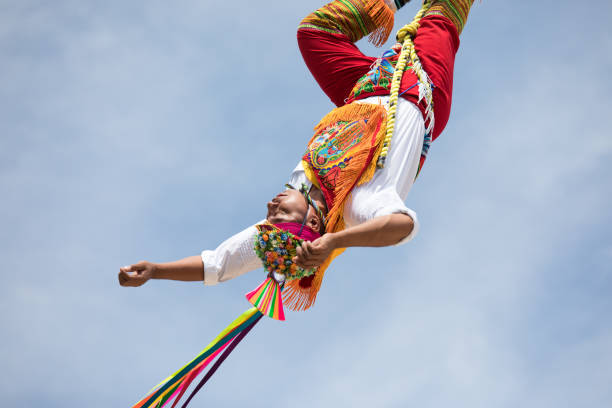 Voladores performing flying men show. Cancun, Mexico - Mar 15, 2017: Traditional flying birdmen performance by voladores: performers throw themselves off a tall wooden pole while rotating towards the ground as part of a ritual ceremony to ask for fertility. volador stock pictures, royalty-free photos & images