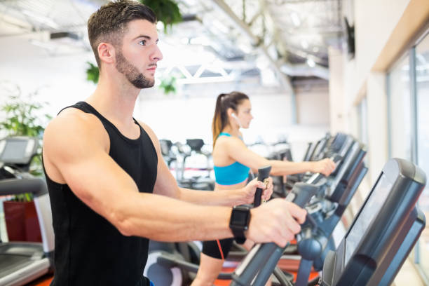 istock Man and woman using ellipitical machines 665076872