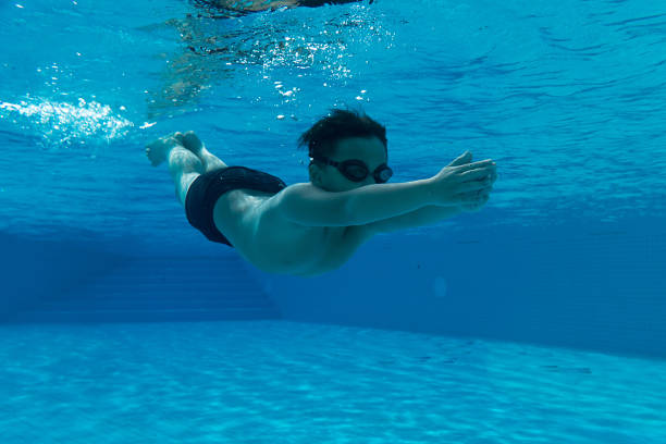 Happy young asian kid with swim goggles underwater
