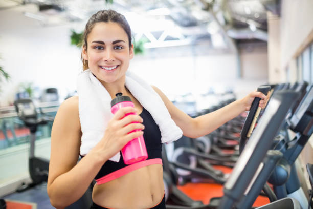 istock Smiling woman drinking on the cross trainer 665081846