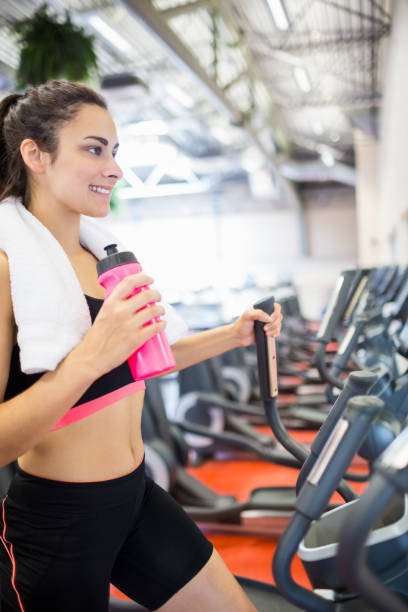 istock Smiling woman drinking on the cross trainer 665081976