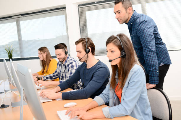 istock group of young people with desktop computer in row and headset training with teacher instructor in customer service call support helpline business center 665107102