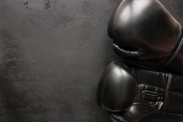 guantes de boxeo sobre un fondo negro - boxing ring combative sport fighting conflict fotografías e imágenes de stock