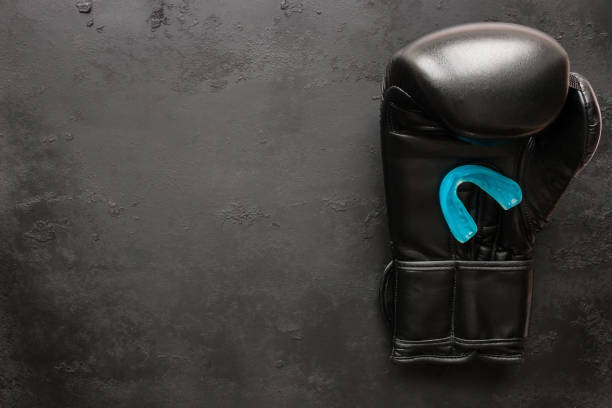 One boxing glove and a mouth guard on a black background with space for text