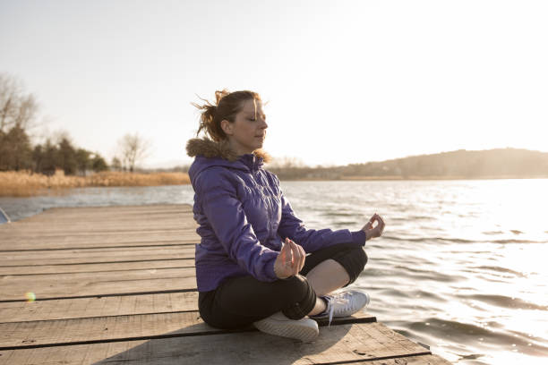 istock young woman meditates on lake pier 665120158