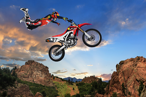 Man performing stunt on motorcycle with mountains in background