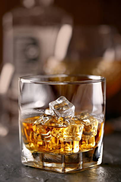 istock Whiskey glass close-up. Cold with ice, bottle in the background 665121248
