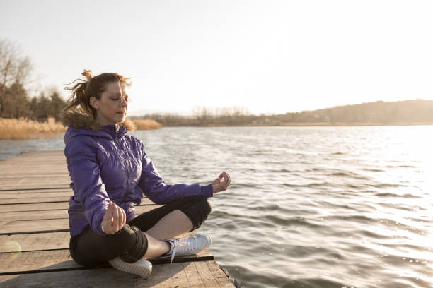 istock young woman meditates on lake pier 665121442