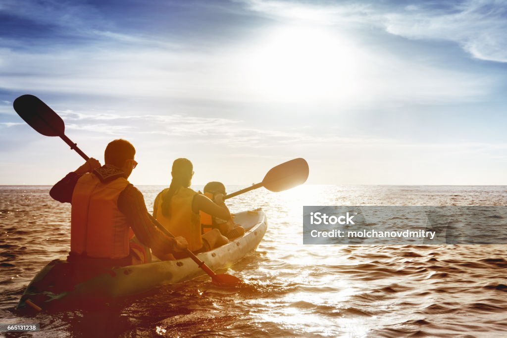 Família de pai mãe e filho caiaque ao pôr do sol do mar - Foto de stock de Família royalty-free