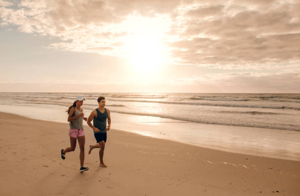 istock Couple running together on the sea shore 665132270