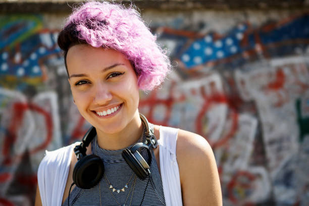 istock Smiling young hipster girl posing against graffiti wall 665132842