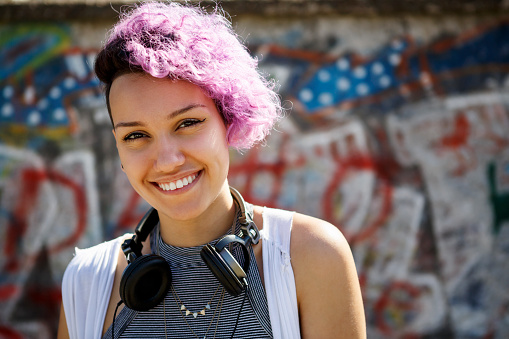 Portrait of a caucasian teenage hipster girl with pink braids using a smartphone on a street background.Summer concept.Generation Z style.Social media concept.Selective focus.