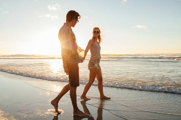 istock Couple walking on the beach together at sunset 665138838