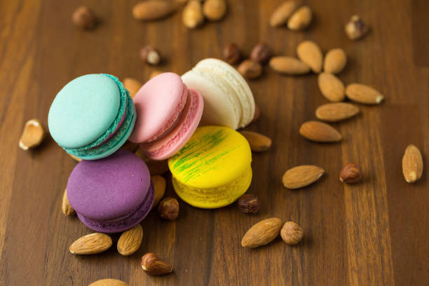 Tasty macaroons and almond on wooden background. Selective focus
