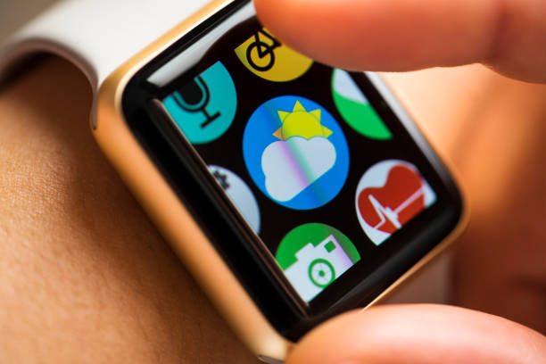 Close up shot of woman wrist wearing smart watch. Finger touching weather forecast app icon on touchscreen.