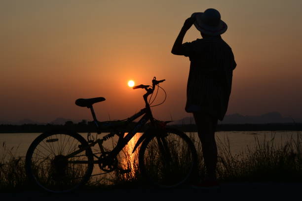 istock people standing with bicycle on nature background, silhouette style 665150032