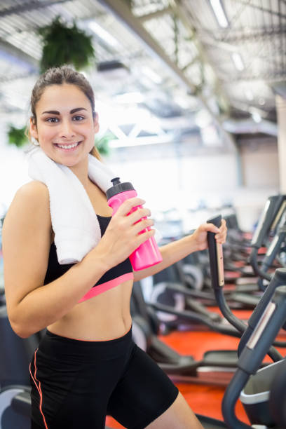 istock Smiling woman drinking on the cross trainer 665162122