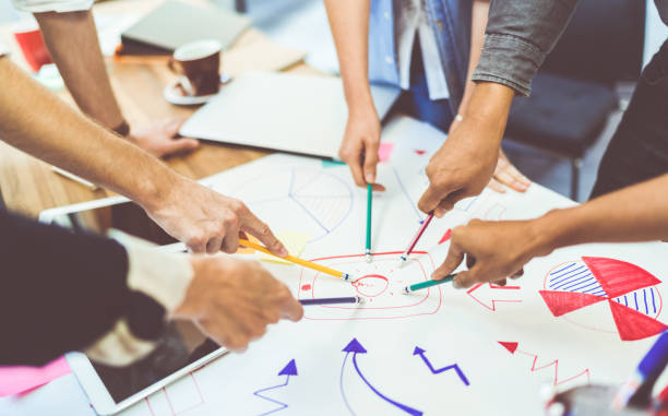 concept de travail d’équipe idée créative. groupe de l’équipe diversifiée multiethnique, partenaire d’affaires ou étudiants en réunion de projet au bureau moderne. cinq personnes pointant à ampoule dessins - par équipe photos et images de collection