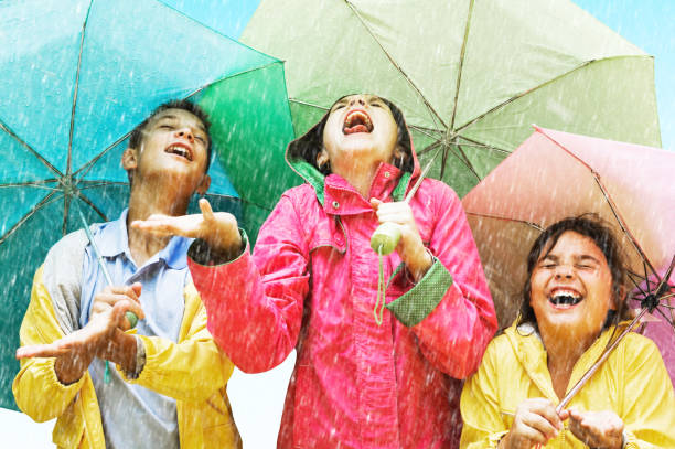 Raining Young girl holding up umbrella in the rain. raincoat photos stock pictures, royalty-free photos & images