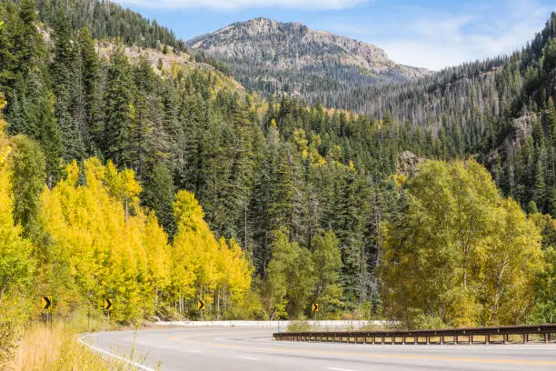 Highway road on mountain with golden aspen trees in Colorado