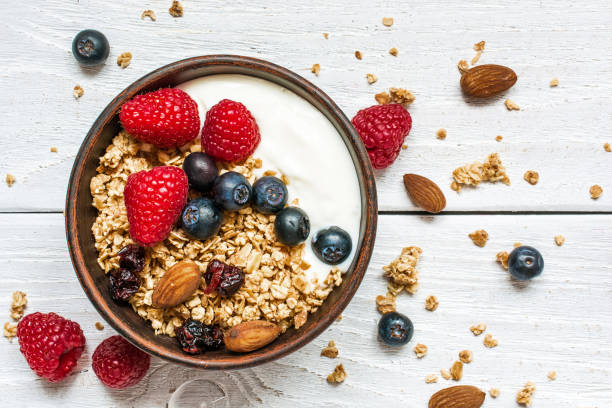 bowl of oat granola with yogurt, fresh raspberries, blueberries - cereal breakfast granola healthy eating imagens e fotografias de stock