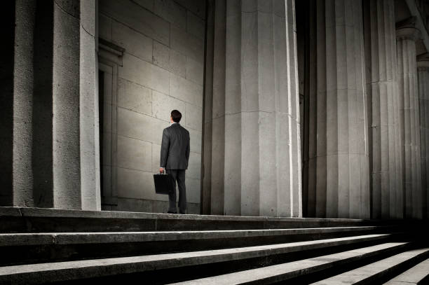 istock Businessman Looking Up At Columns Carrying A Briefcase 665206646