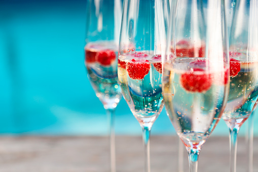 Champagne glasses with raspberry. Summer pool party