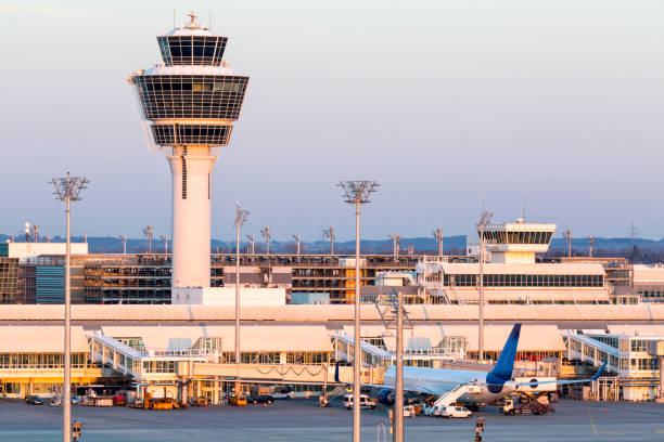 Franz-Josef-Strauss Munich airport with control tower, passenger airplane standing at the gates, apron area, long exposure with tripod.