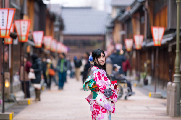 Young woman in Kimono looking over shoulder, in the middle of Higashi Chaya district, Kanazawa, Japan