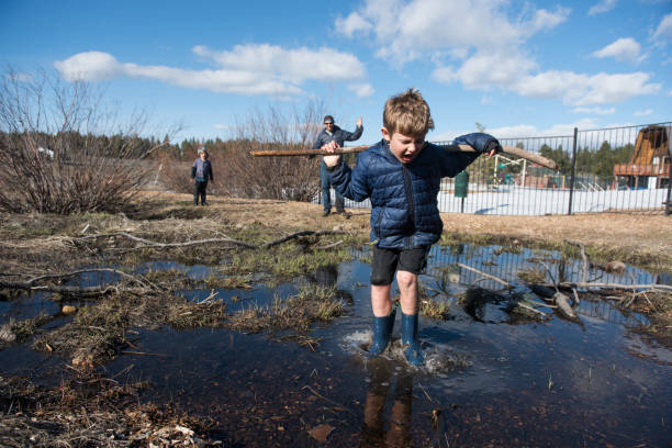 istock Child jumping into big puddle with angry dad watching 665263212