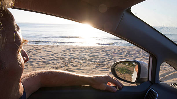 istock Man pauses driving to admire view by sea shore 665267907