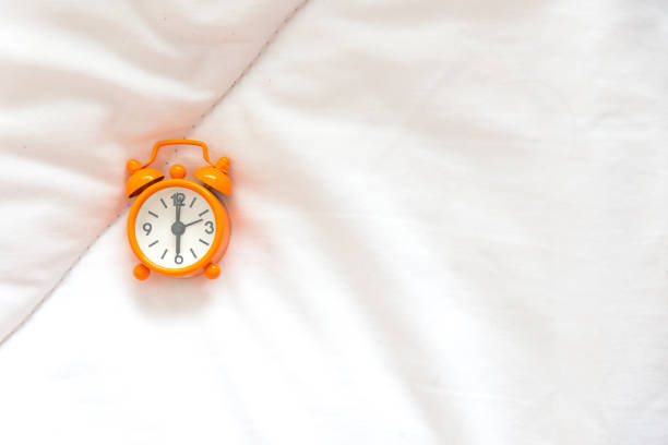 istock Alarm clock on bed in morning with sun light 665280772