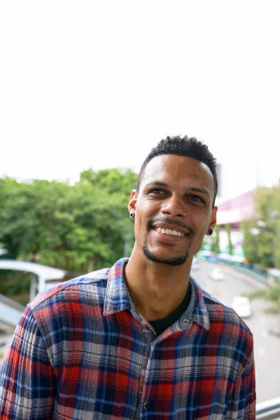 istock Young happy African man smiling while thinking against view of the footbridge 665280904