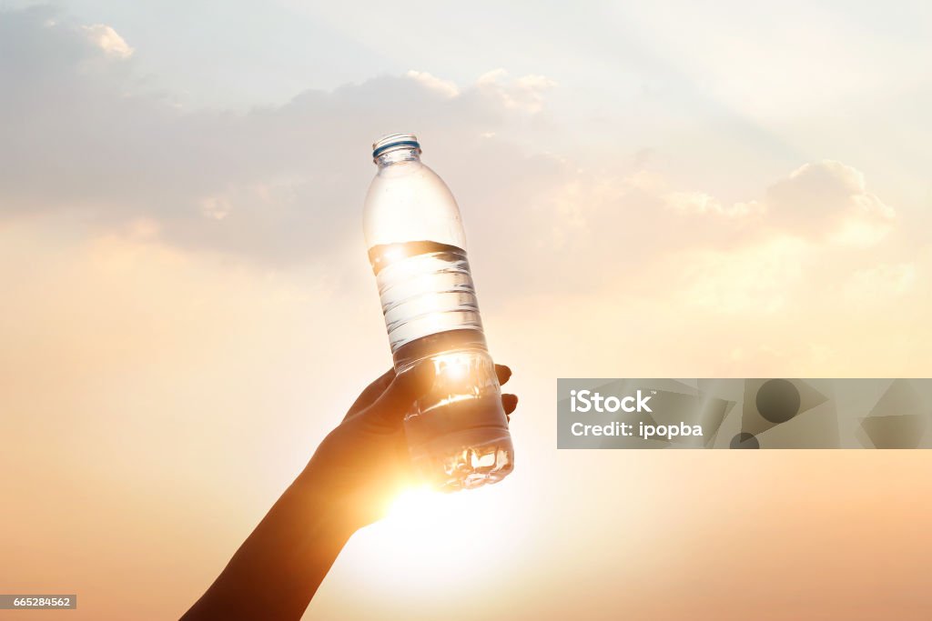 Hand mit Trinkwasser auf Sonnenuntergang Hintergrund - Lizenzfrei Trinken Stock-Foto