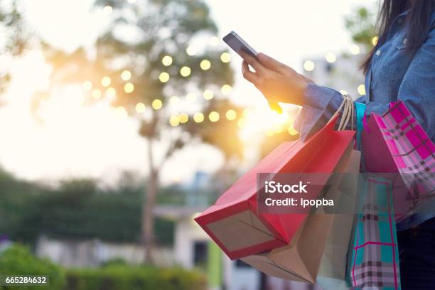 Woman Using Smartphone With Shopping Bag In Hands Stock Photo - Download Image Now - Retail, Shopping, Vacations