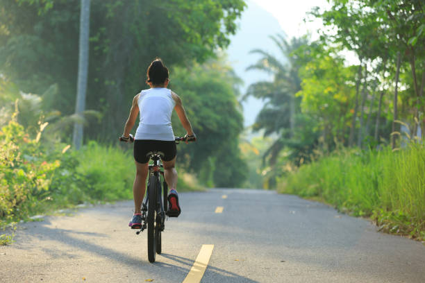 istock Young  woman cycling on tropical forest trail 665297870