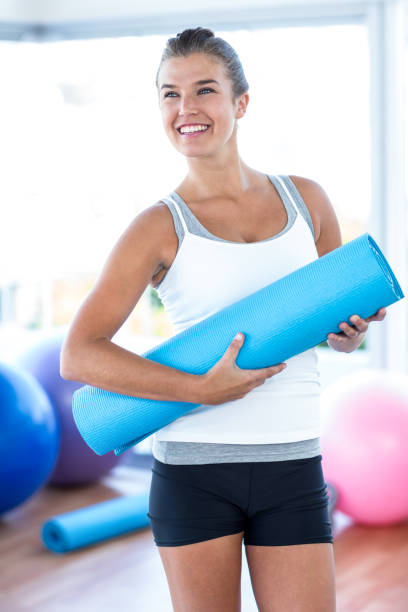 istock Beautiful woman smiling while holding yoga mat 665298734
