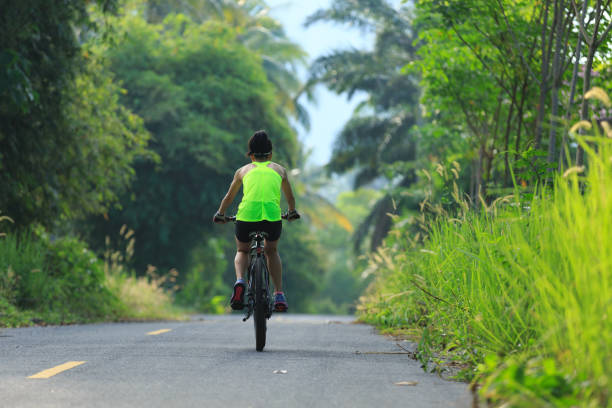 istock Young  woman cycling on tropical forest trail 665304758