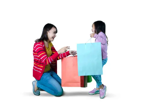 mage of young mother and daughter opening shopping bags, isolated on white background