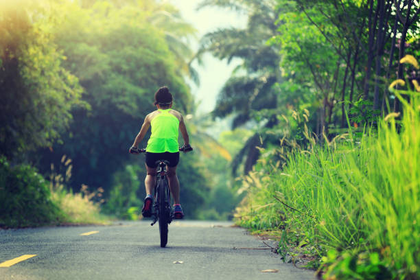 istock Young  woman cycling on tropical forest trail 665308248
