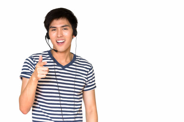 istock Studio shot of happy Asian customer service representative smiling and pointing at camera against white background 665308928