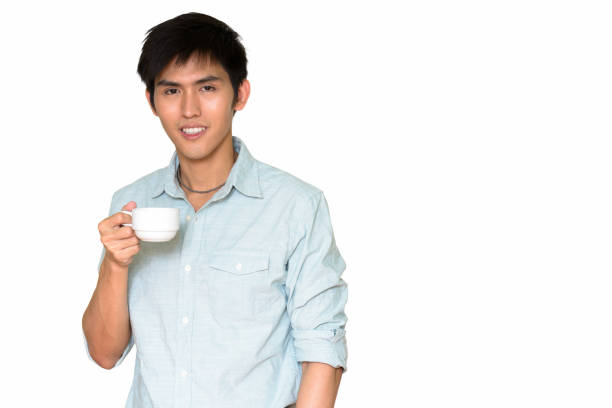 istock Studio shot of young happy Asian man smiling while holding coffee cup isolated against white background 665309064
