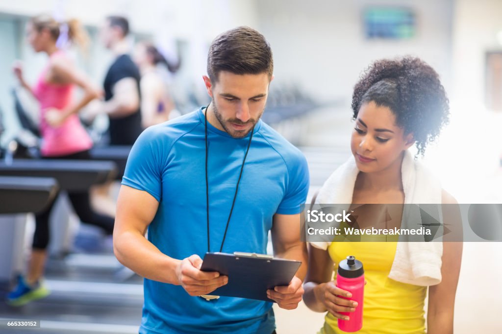 Fit woman talking to her trainer Fit woman talking to her trainer at the gym Fitness Instructor Stock Photo