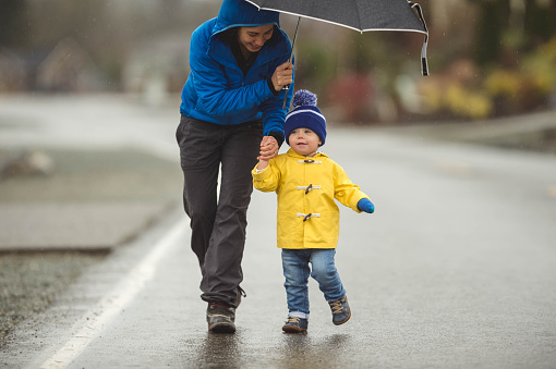 Young mom doesn't let the rain stop her from taking her young boy on a joyful walk