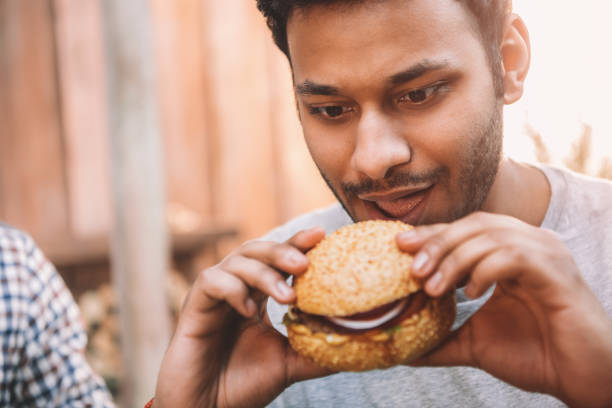 istock Hungry young man holding and looking at fresh tasty hamburger 665338212
