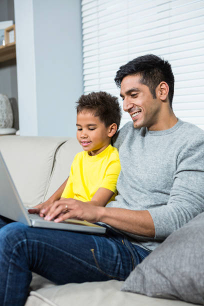 istock Smiling father and son using laptop on the sofa 665341270