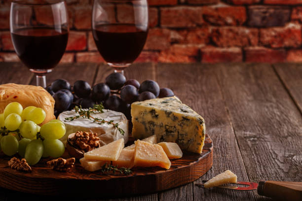 istock Cheese, nuts, grapes and red wine on wooden background 665344786