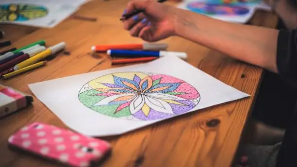 Photo of A girl drawing a mandala