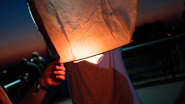 istock People lighting flying lanterns at night as part of ritual 665357014