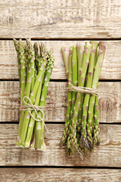 istock Bunch of green asparagus on grey wooden table 665357340